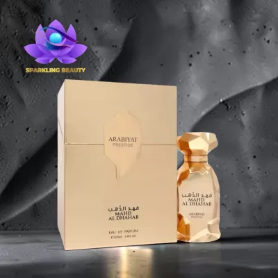 Perfume dourado facetado com caixa bege e texto preto e dourado colocado sobre superfície cinza