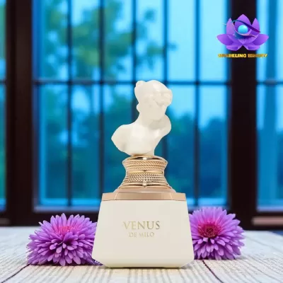 Frasco de perfume branco com busto clássico como tampa, texto VENUS DI MILO, flores roxas ao lado, fundo com janela