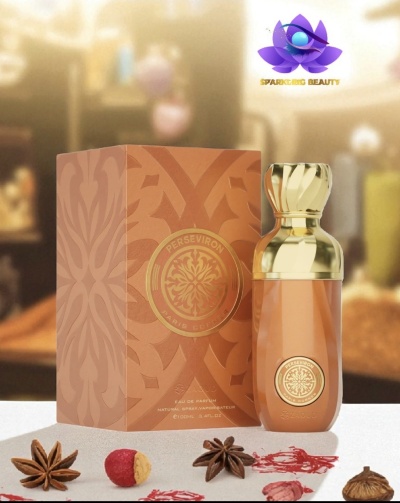 Frasco de perfume dourado com caixa castanha ao lado, especiarias na frente e fundo desfocado.