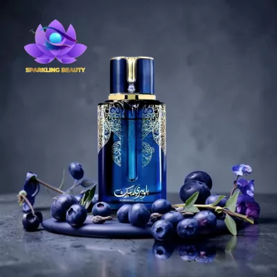 Frasco de perfume azul com detalhes dourados rodeado por mirtilos frescos e flores violeta