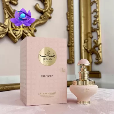 Frasco de perfume rosa claro com detalhes dourados e caixa texturizada rosa com texto, sobre superfície e fundo decorado.