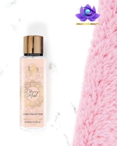 Frasco de spray corporal Cherry Musk com tampa dourada ao lado de tecido felpudo rosa