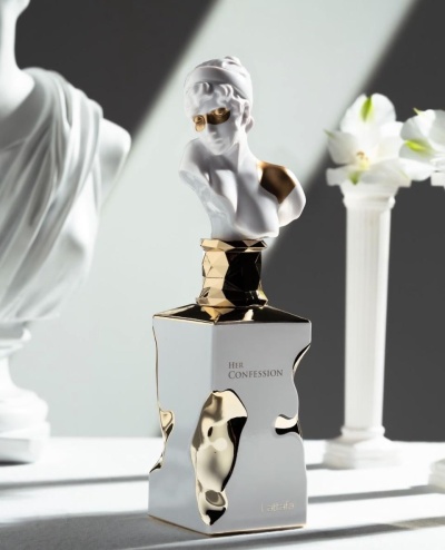 Frasco de perfume prateado e dourado com estátua branca no topo