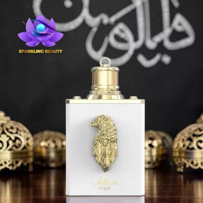 Frasco de perfume branco com relevo dourado de águia e texto UQAB