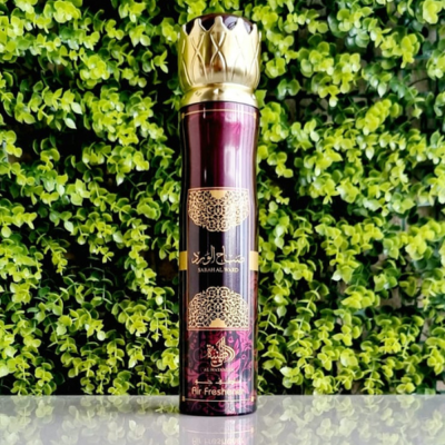 Frasco de spray roxo metálico com tampa dourada contra fundo de folhas verdes