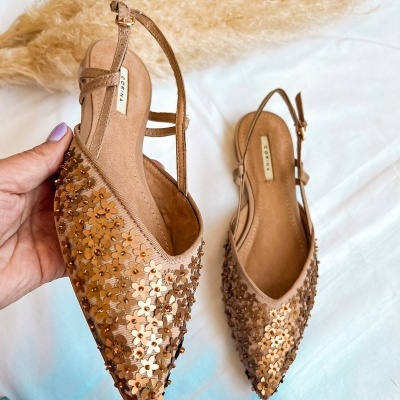 Sapatilhas cor de pele com flores douradas aplicadas e tiras ajustáveis.