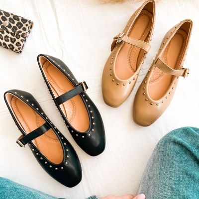 Dois pares de sapatilhas Mary Jane com tachas douradas e fivela, preto e bege, em tecido branco, com carteira de leopardo e mão com relógio.