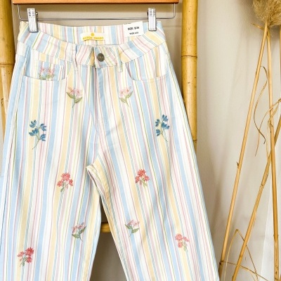Calças com padrão às riscas e bordados florais penduradas em cabide