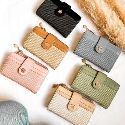 Seis carteiras em diferentes cores sobre tecido branco com plantas decorativas