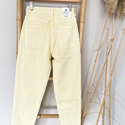 Calças de ganga amarelas claras penduradas numa estrutura de bambu