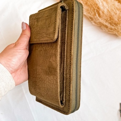 Carteira castanha texturada com fechos segurada por mão feminina