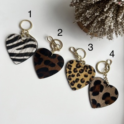 Quatro porta-chaves com padrão animal em forma de coração numerados de 1 a 4 sobre fundo branco.