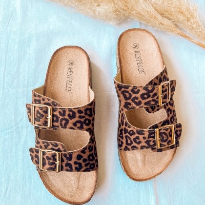 Sanitas com padrão leopardo e fivelas douradas sobre tecido azul claro