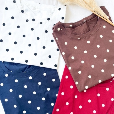 T-shirts de algodão com padrão de bolinhas em várias cores sobre fundo branco com flores secas.