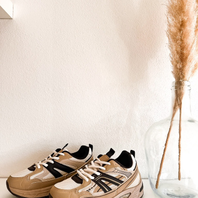 Ténis desportivos beige, branco e preto com vaso de vidro e ramos secos