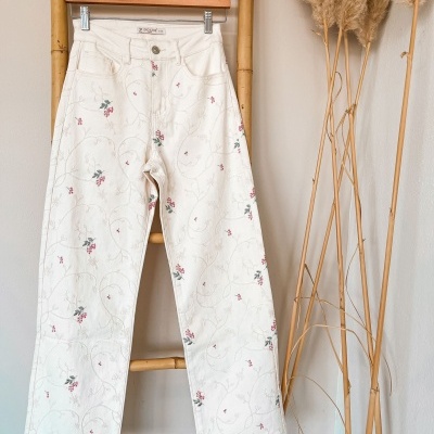 Calças brancas bordadas com flores penduradas numa escada de bambu