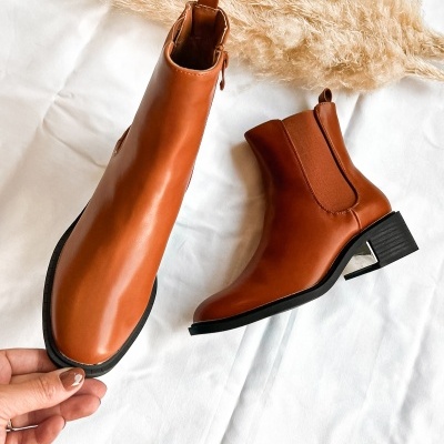 Botas castanhas de cano curto com salto e elástico lateral sobre tecido branco