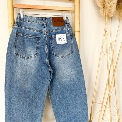 Calças de ganga azuis de corte boyfriend penduradas em cabide de madeira