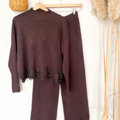 Conjunto de roupa castanha com renda decorativa pendurado na parede