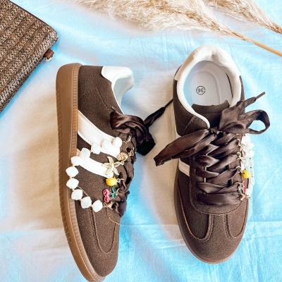 Ténis castanhos com atacadores de cetim decorados com pulseira de conchas e pendentes