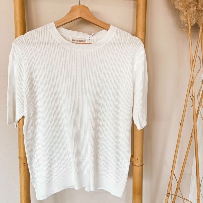 Camisola branca de malha com riscas verticais pendurada num cabide