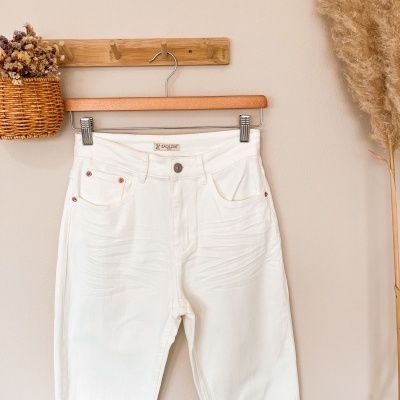 Calças brancas de tecido denim penduradas num cabide de madeira