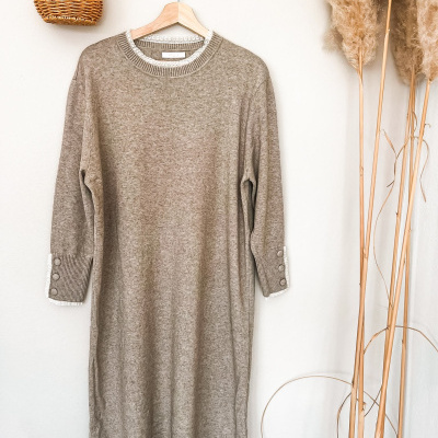 Vestido bege de malha pendurado com detalhes em renda e botões junto a decoração natural