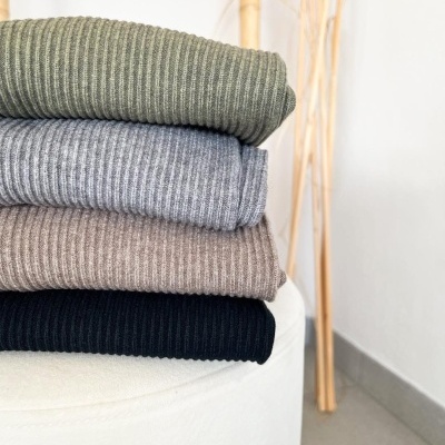 Quatro roupas caneladas coloridas empilhadas sobre um assento branco