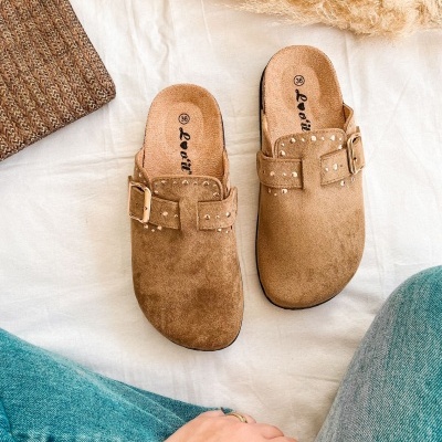 Chinelos castanhos em camurça com fivela dourada e detalhes em tachas sobre tecido branco