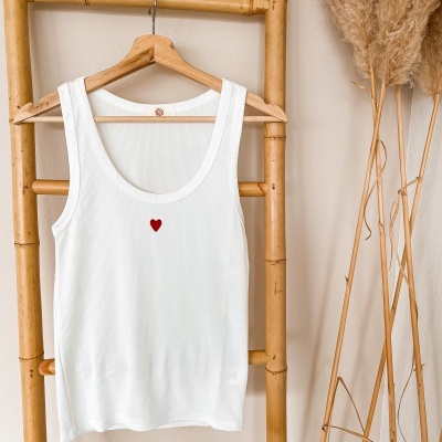 Camisola branca sem mangas com coração vermelho pendurada numa escada de bambu