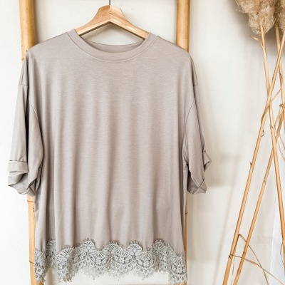T-shirt bege claro com renda branca na bainha pendurada em escada de bambu