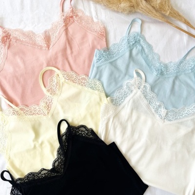 Conjunto de tops femininos com alças e renda em várias cores sobre tecido branco e ramo seco