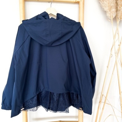 Casaco azul escuro com capuz e renda pendurado numa estrutura de madeira