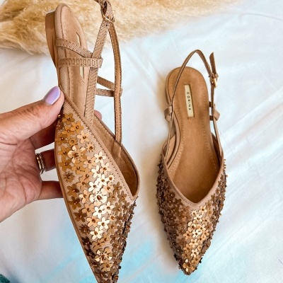 Sapatos rasos bege com flores douradas decorativas e tira ajustável no calcanhar