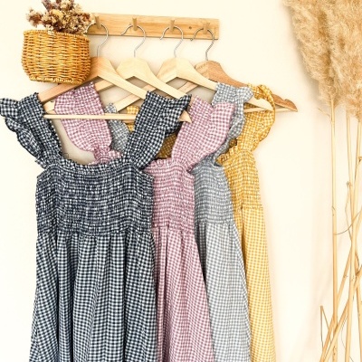 Vestidos às riscas em padrão xadrez pendurados em cabides de madeira com decoração de flores secas