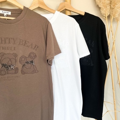 Três t-shirts de algodão coloridas penduradas em cabides com ursinhos e texto estampado