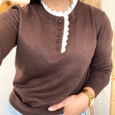 Camisola castanha de malha com botões e renda branca na gola, calças de ganga e relógio dourado.