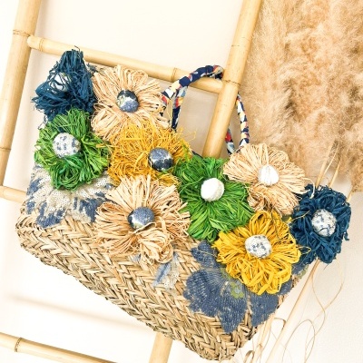 Mala de verga trançada com flores coloridas pendurada numa escada de bambu