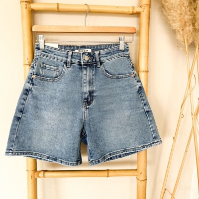 Calções de ganga azuis pendurados em cabide numa estrutura de bambu