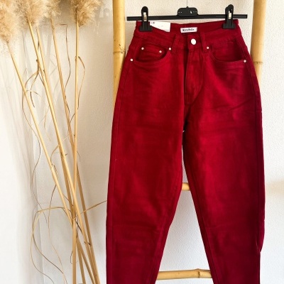 Calças vermelhas penduradas em estrutura de bambu ao lado de palha decorativa