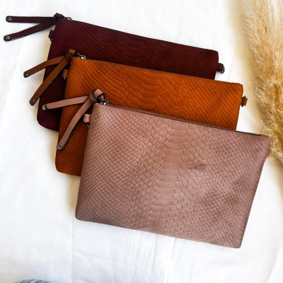 Três bolsas retangulares com textura tipo pele de cobra em tons castanho, alaranjado e rosa claro