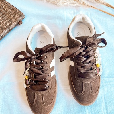 Ténis castanhos com fitas de cetim e contas coloridas, tamanho 36, sobre tecido azul com decoração natural.