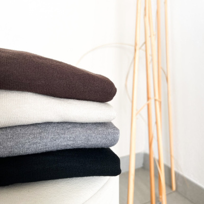 Pilhas de camisolas de malha em quatro cores diferentes sobre superfície branca