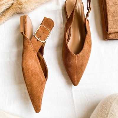 Sapatos de camurça castanha com fivela dourada sobre tecido branco