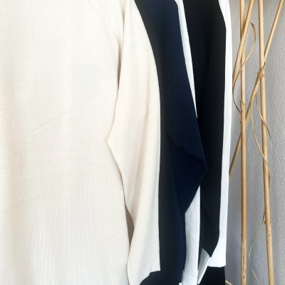 Camisolas de malha em tons neutros penduradas parede com ramos secos