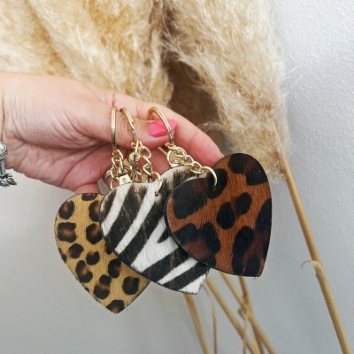 Porta-chaves em forma de coração com padrões animal print segurados por mão feminina com unhas rosa