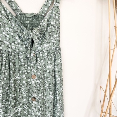 Vestido verde floral com botões de madeira pendurado num cabide
