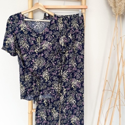 Conjunto de pijama floral azul escuro com camisola e calças pendurado em cabide de madeira