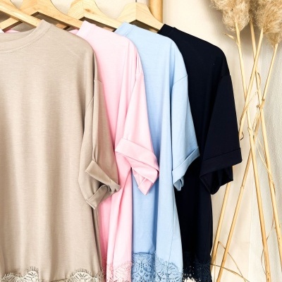T-shirts com barra em renda em várias cores penduradas num cabide de madeira