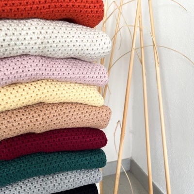 Pilhas de tecidos de malha em várias cores com padrão de pequenos buracos